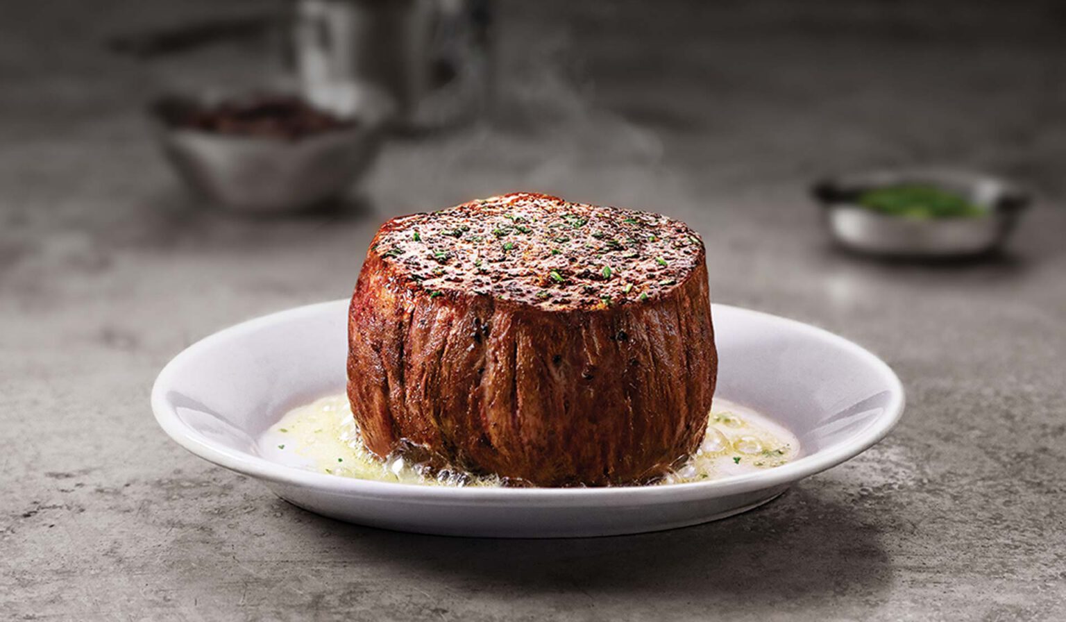 A close up of a filet mignon with butter on a plate