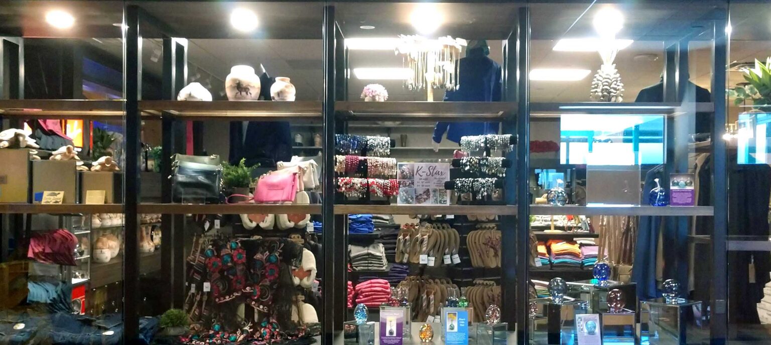 A retail display featuring neatly arranged stacks of colorful jewerly, includingbags and bracelets, on multiple shelves. The setting has bright lighting and decorative elements, with a variety of other merchandise visible in the background.